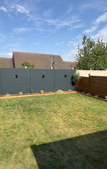 Jardin aménagé par Verdevillage : pelouse, clôture anthracite et bordures plantées près de Valenciennes